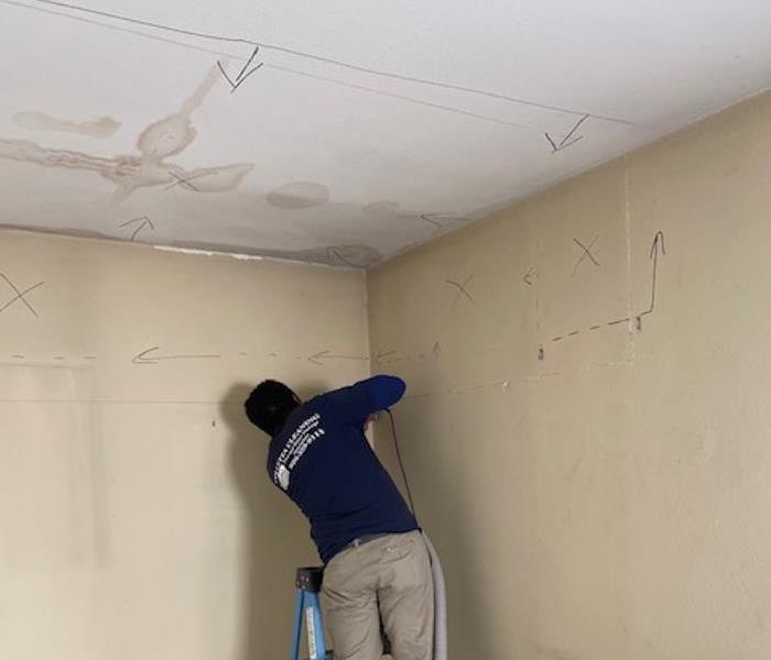 SERVPRO technicians using equipment on a wall with markings 