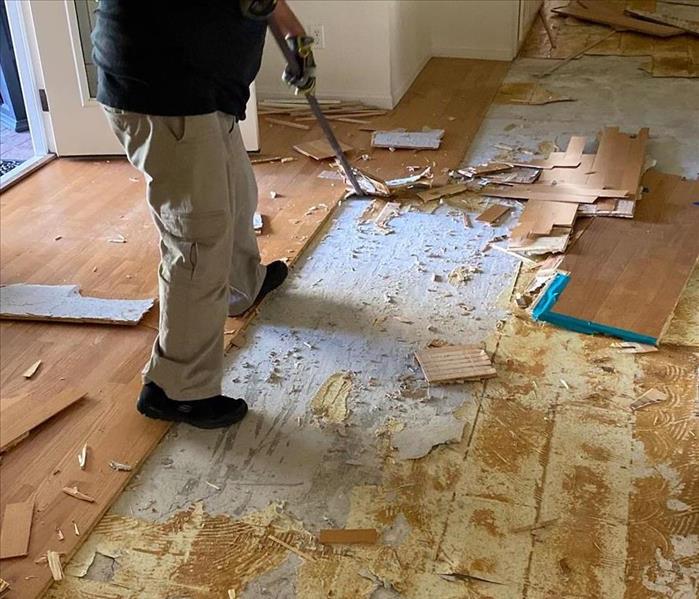 A man ripping wood flooring up. 